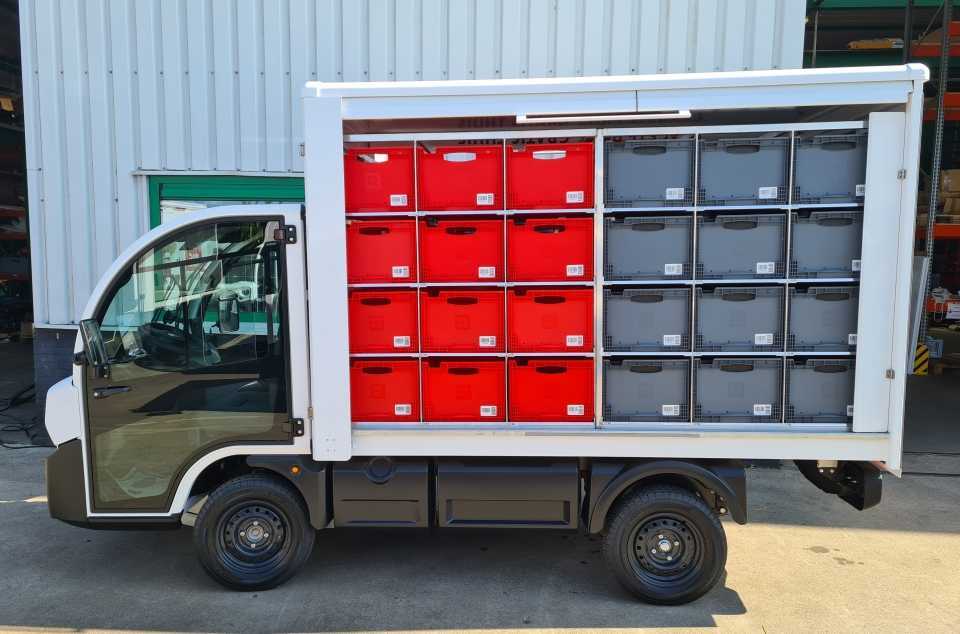 Zijaanzicht van een Picnic-bezorgwagen op basis van de Goupil G4, met vakken vol rode en grijze boodschappenkratten